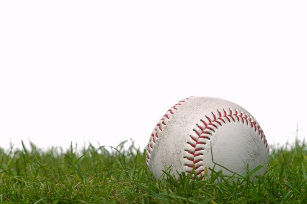 Studio shot of a baseball on grass, white background.