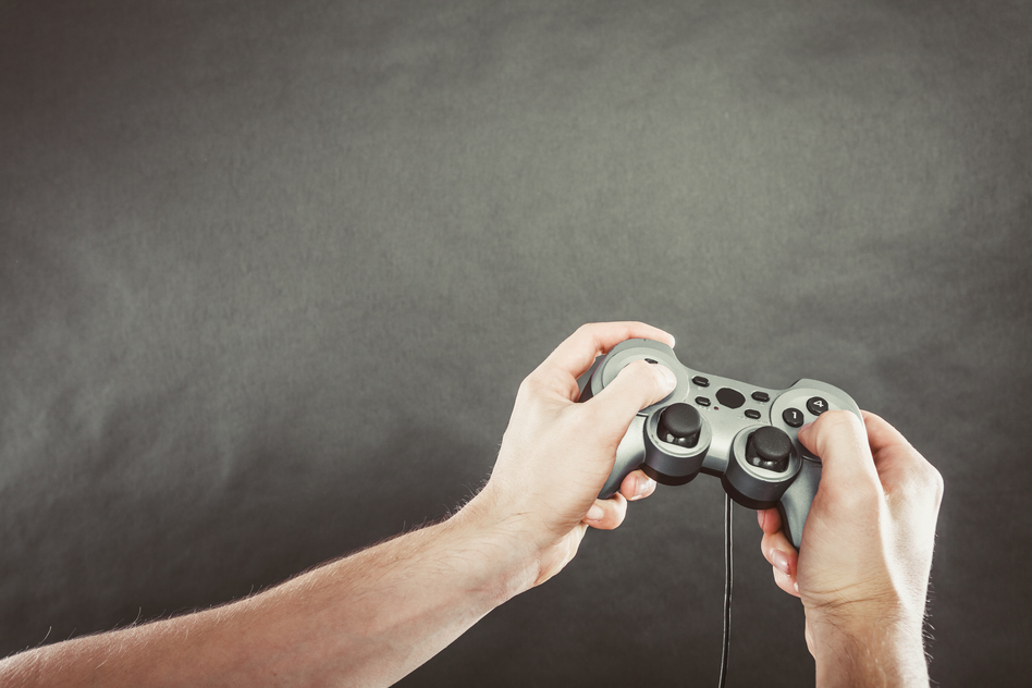 Playing games concept. Part body man with joystick play game on console playstation. Male hands holding grey pad.