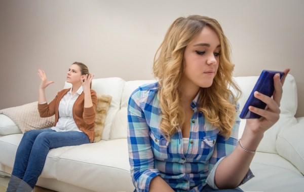 Teenage daughter looking messages in a smartphone and ignoring her furious mother. Bad family communication concept by new technologies