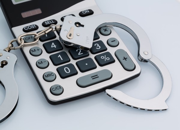 calculators and handcuffs on a white background. representative photo of white-collar crime