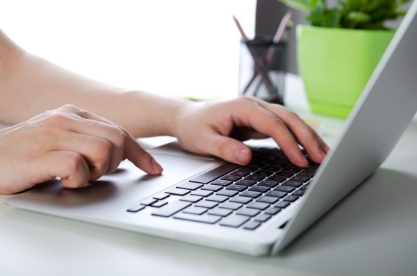 Man working with modern laptop in office. Hands typing on keyboard