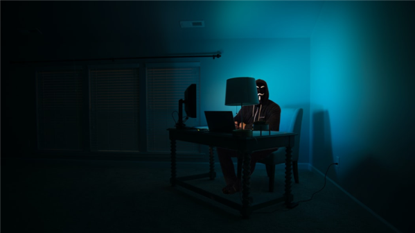 hooded person using a laptop in the dark