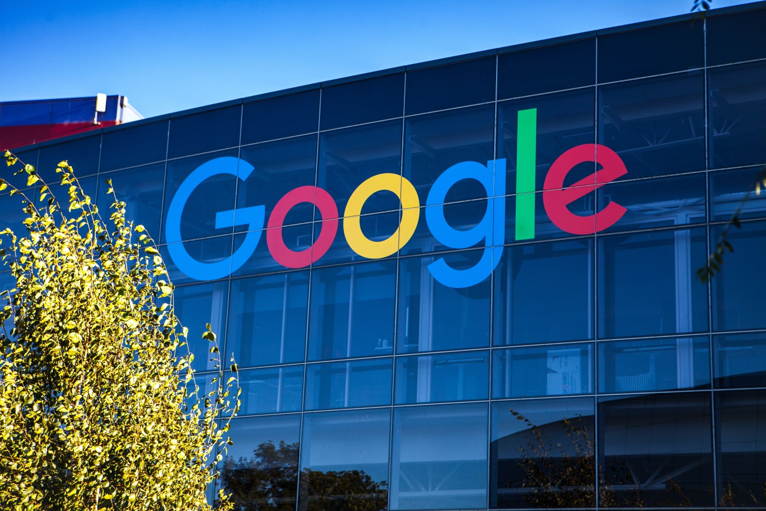Edifício de vidro contra um céu azul, com o logotipo do Google no prédio