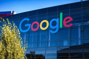 Glass building against a blue sky with the Google logo on the building