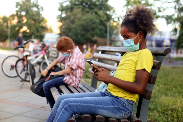 Two kids in a schoolyard during coronavirus pandemic. Both about 10 years old, African female and Caucasian male.