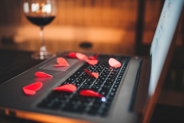 Red hearts on the computer keyboard and glass with red wine. Online dating, Valentines day concept.