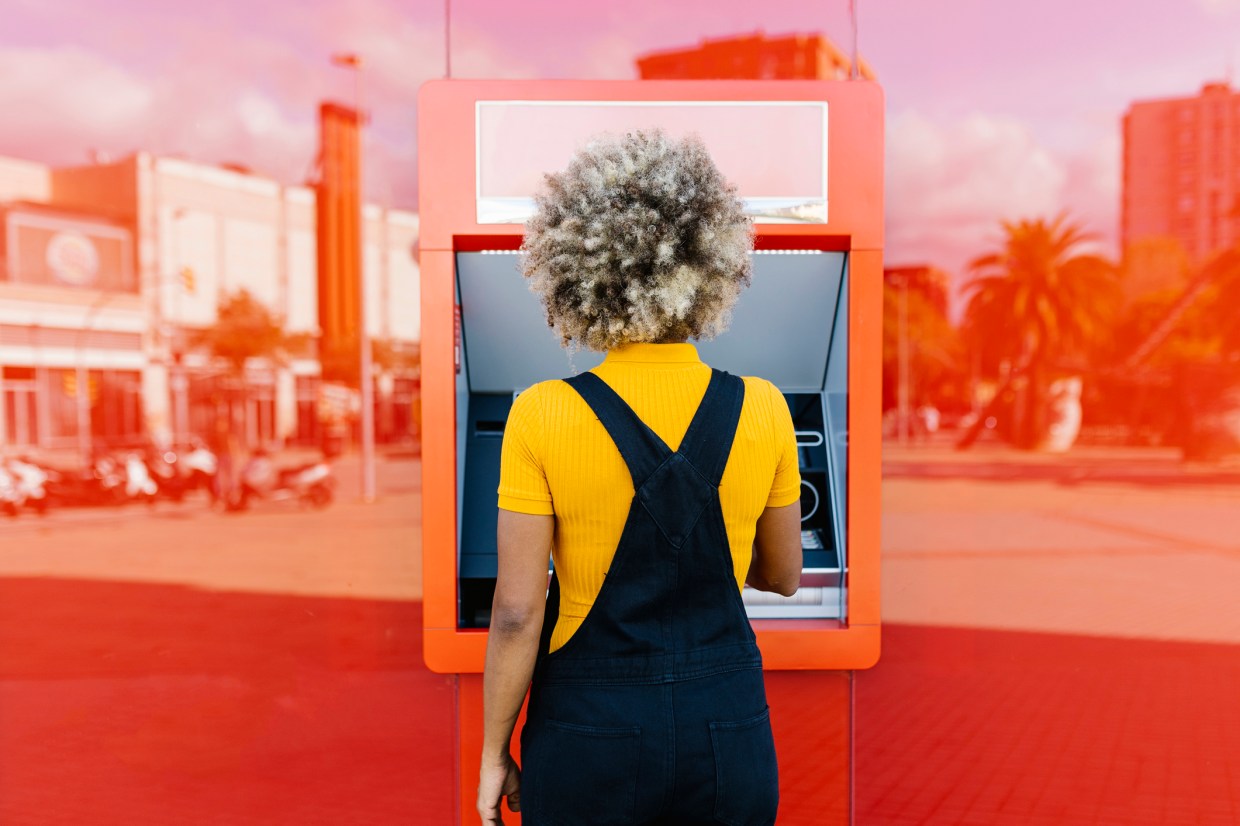 Woman with afro hairstyle using red ATM machine
