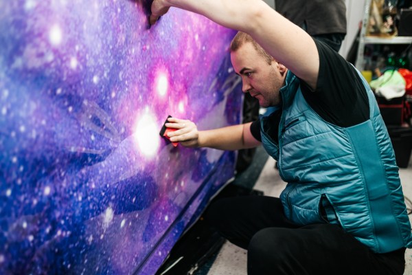 Car wrapping specialist putting vinyl foil or film on car. Selective focus.