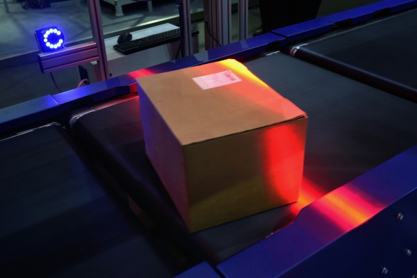 Automatic sensor scanning at logistics factory's conveyor belt.