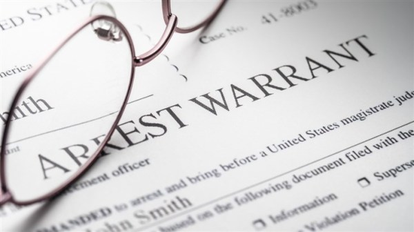 reading glasses on top of an arrest warrant