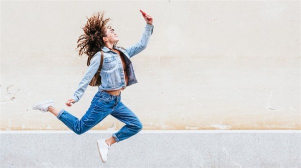 Woman with cell phone jumping for joy