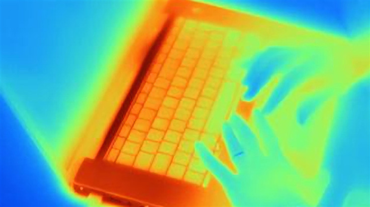hands on laptop under a thermal scanner