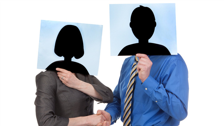 two people in business attire shaking hands while holding up faceless photos
