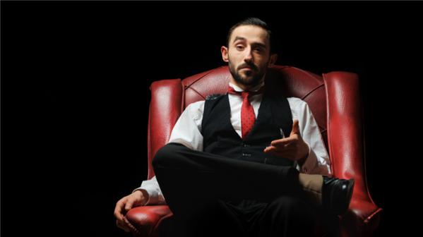 man sitting in leather chair against dark background