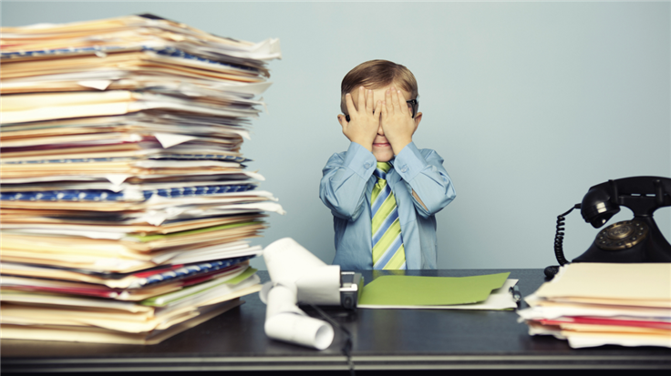 disappointed kid behind pile of files and business calculator