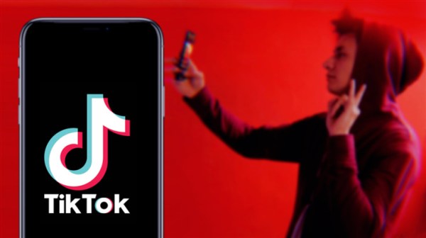 TikTok logo on phone with hooded male teen on background doing selfie