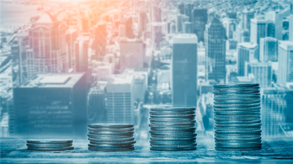 growing piles of coins with background of a financial district