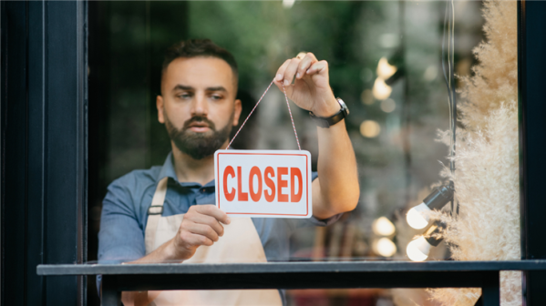 Man hanging up Closed sign