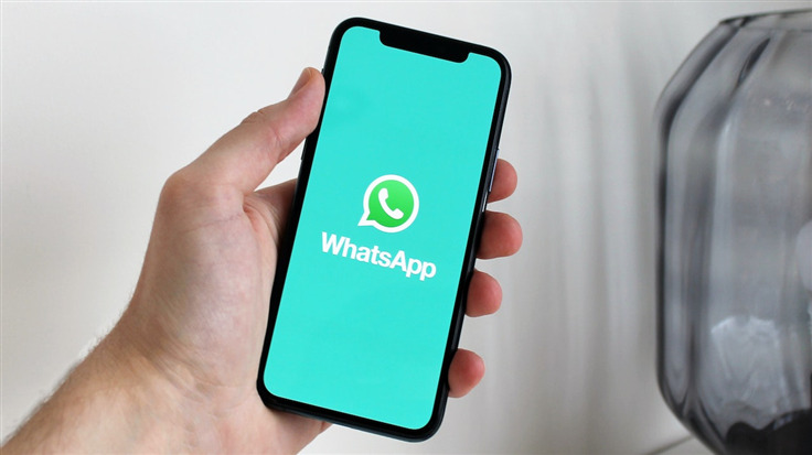 hand holding smartphone with WhatsApp logo