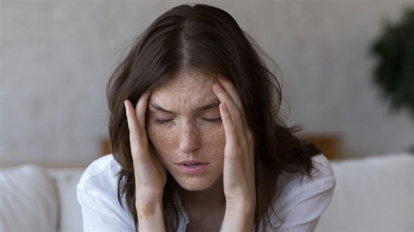 A young lady holding her head in agony