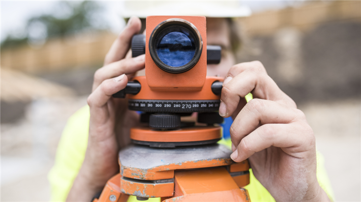 construction worker using a theodolite for triangulation