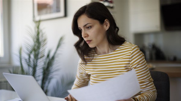 woman comparing a paper form with her laptop screen