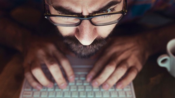 bearded man typing with his nose almost on the keyboard
