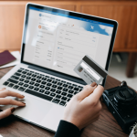 Someone looking at their credit card while at a computer