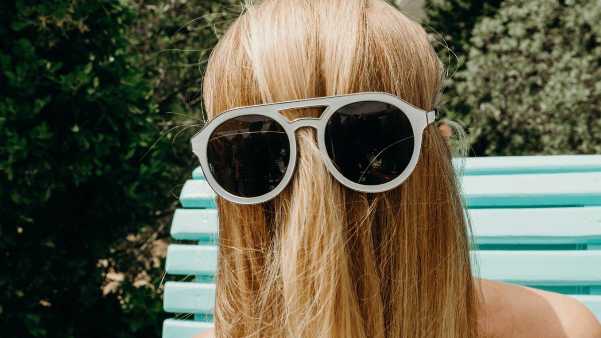 A person with their long hair over their face wearing sunglasses