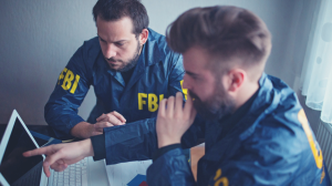 Two FBI agents working together on a laptop