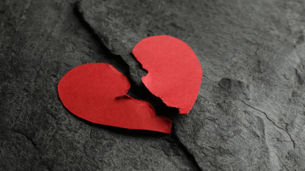 A heart shaped piece of paper that has been ripped down the middle