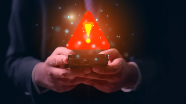 Two hands holding a phone with a warning triangle above the phone