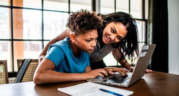 Teen learning to use a laptop with parent