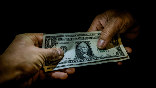 One hand passing US dollars to another hand