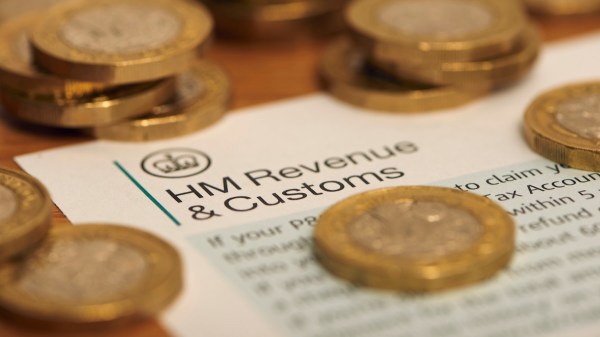 A letter from HMRC is laid flat on a table with English pound coins scattered across.
