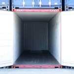 A cargo container is opened up amidst other containers. It is entirely empty.