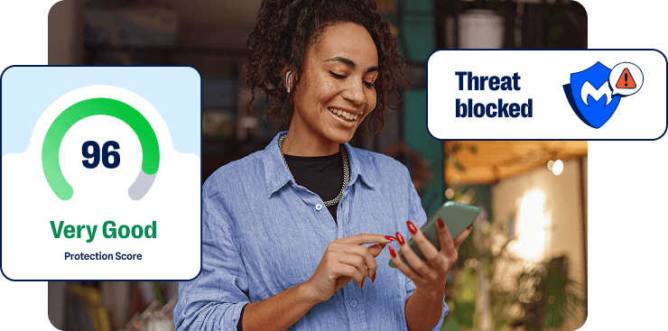 Photo of a woman looking at a mobile phone in a rool full of plants. Callouts from the Malwarebytes interface show a 96 score and the phrase Threat Blocked