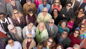 A group of people wearing a variety of sunglasses looking up at the sky and into the camera