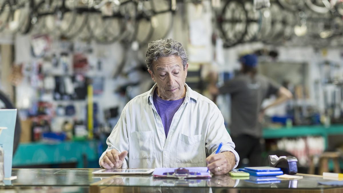 Caucasian man in bicycle shop writing on clipboard