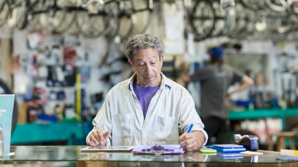 Caucasian man in bicycle shop writing on clipboard