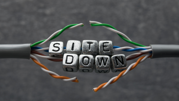 Drahtgitter mit Metallwürfeln, auf denen die Buchstaben „SITE DOWN“ zu sehen sind